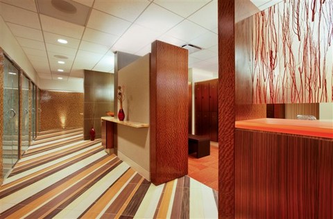 Interior of office building with striped floors, frosted glass doors and custom shelves build into wall dividers. A red vase sits on the central shelf.