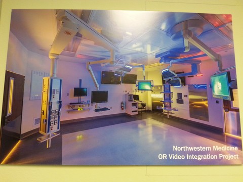 Photograph of custom woodwork in a a hospital room. Multiple monitors and screens are on display, and text in lower right corner reads 'Northwestern Medicine OR Video Integration Project'