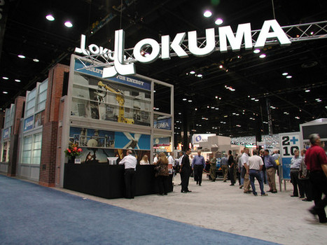 Trade show attendees and custom exhibits. Lit signs show name of Lokuma company