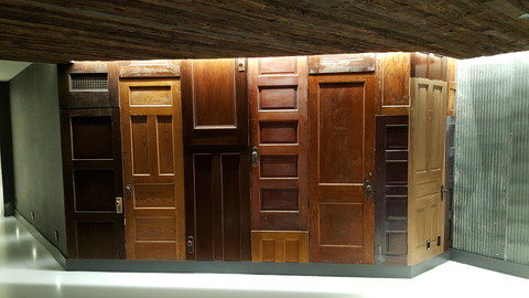 Cain Millwork wooden door display at The Renaissance hotel. Multiple wooden doors in different color and patterns set into a wall with brass doorknobs.