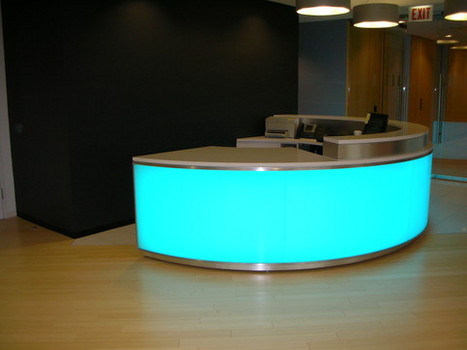 Round reception desk with side panels lit in bright blue.