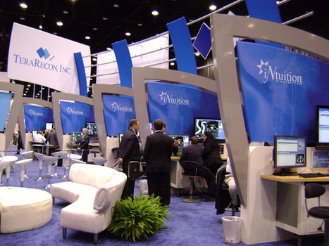 A row of matching cubicles on display at trade show. Hanging Sign for TeraRecon Inc and Cubicles have computers and signs that state iNutrition