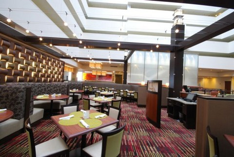 Hotel dining room with custom woodwork. Tables and booths are shown set with placements and a decorative lit wall.