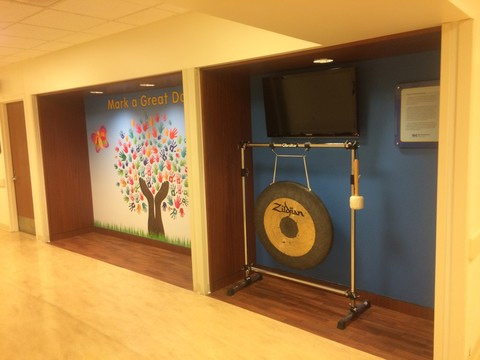 Donor Wall at Cain Millwork with an artistic tree design that shows handprints for leaves, a large gong, and television monitor.