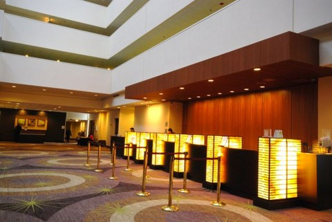 Hotel lobby with custom woodwork. Gold aisle dividers with red ropes separate access to reception lines, and the carpet has a circle and star pattern.